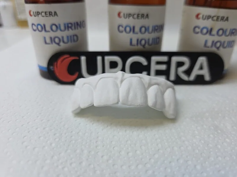 Zirconia in fase green davanti ai flaconi di colorazione Upcera